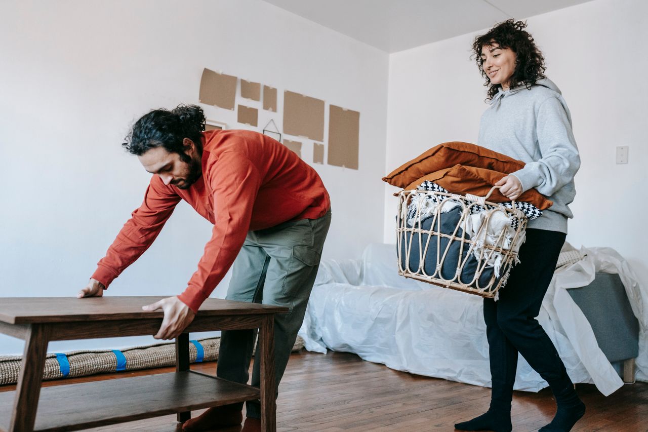 A couple arranging furniture and packing in a contemporary apartment ahead of a move.